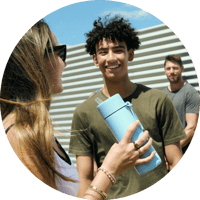 A young adult man and young adult female talking with another male friend in the background A young adult man and young adult female talking with another male friend in the background